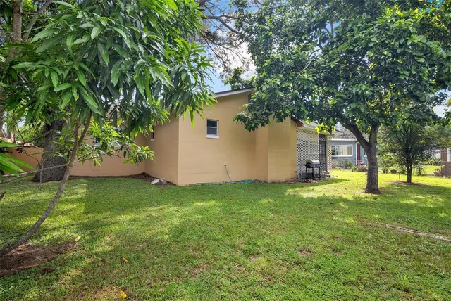 a backyard of a house with plants and large tree