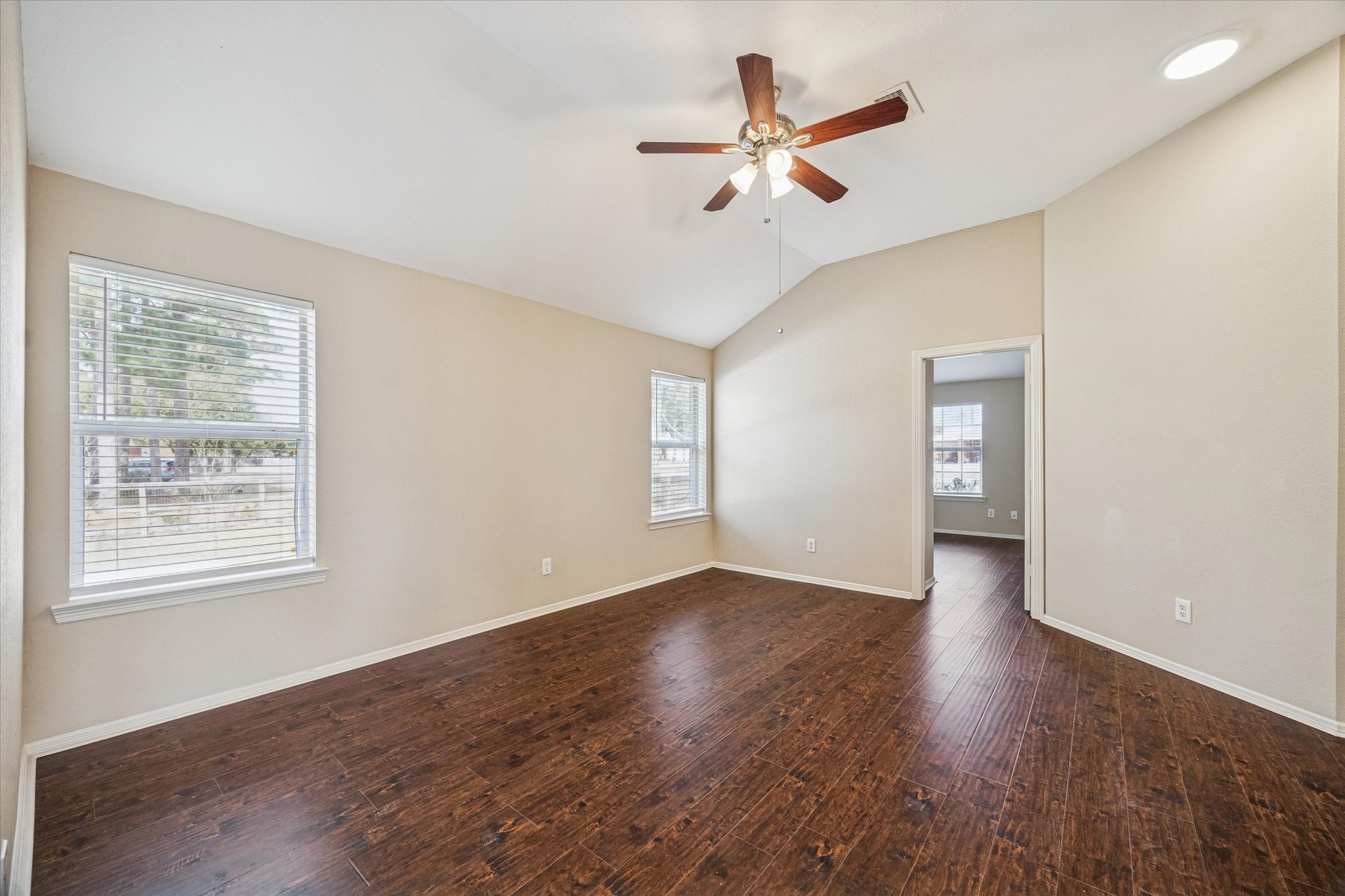 19034 Ranchcrest Drive Magnolia, TX 77355 - Photo 14 of 26 This room features rich hardwood floors, neutral walls, and a vaulted ceiling with a ceiling fan. Natural light streams through two large windows, creating a bright and inviting space.