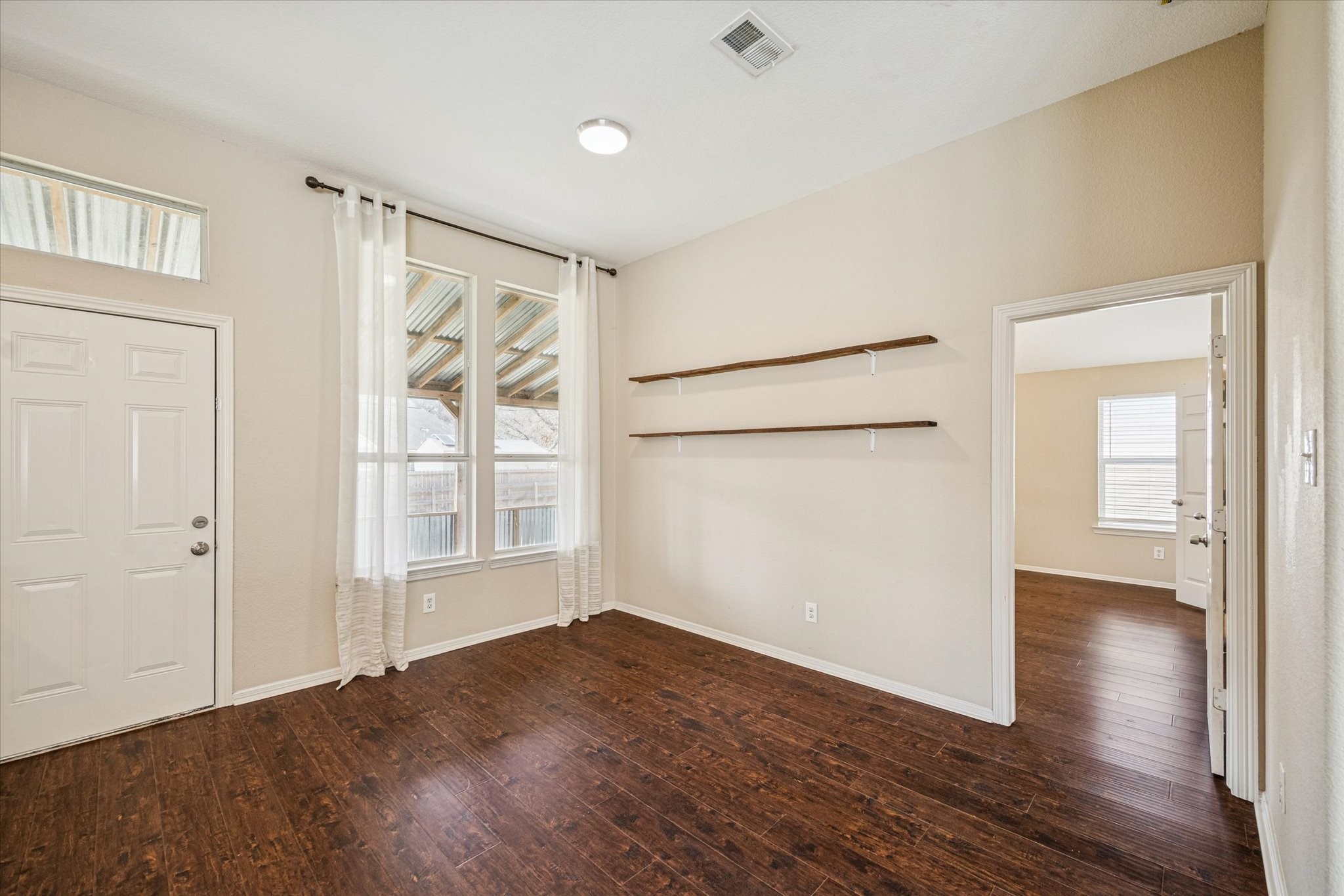 19034 Ranchcrest Drive Magnolia, TX 77355 - Photo 16 of 26 This room features warm wooden flooring and neutral walls, with large windows bringing in natural light. It includes built-in shelves and connects to another room, offering versatile living space.