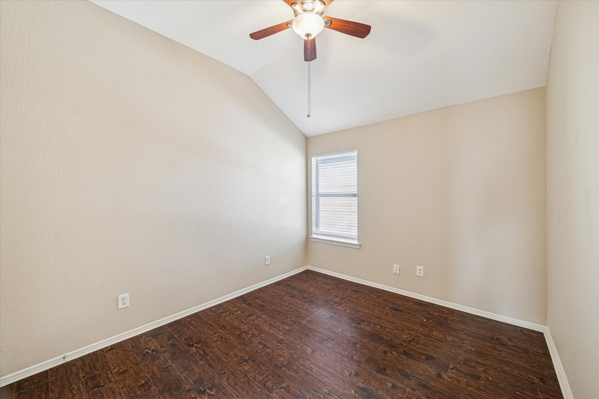 19034 Ranchcrest Drive Magnolia, TX 77355 - Photo 18 of 26 This room features a vaulted ceiling with a ceiling fan, neutral walls, and dark wood flooring. A window provides natural light, making it ideal for a cozy bedroom or office space.