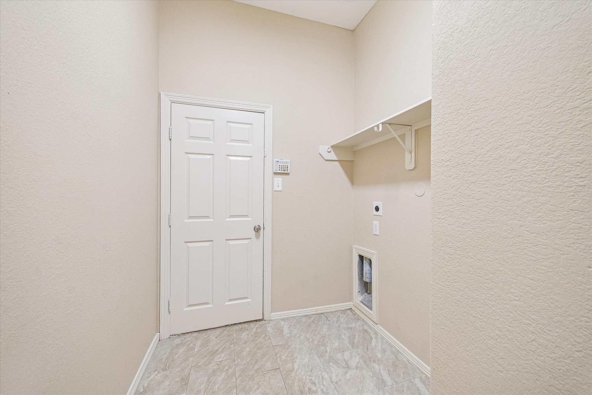 19034 Ranchcrest Drive Magnolia, TX 77355 - Photo 21 of 26 This room appears to be a laundry area with light-colored walls and tiled flooring. It features a white door, a wall-mounted shelf, and connections for a washer and dryer.