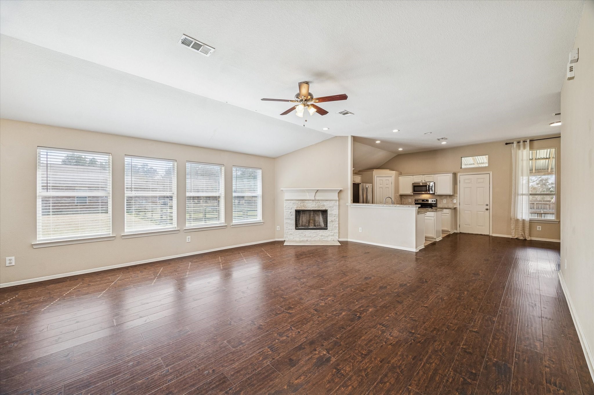 19034 Ranchcrest Drive Magnolia, TX 77355 - Photo 3 of 26 This spacious living area features hardwood floors, a cozy fireplace, and abundant natural light from multiple windows. The open-concept layout flows into a modern kitchen with stainless steel appliances, perfect for entertaining.