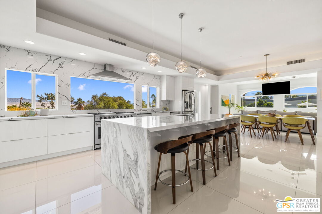 775 West Racquet Club Road Palm Springs, CA 92262 - Photo 3 of 38 a kitchen with stainless steel appliances kitchen island granite countertop a table chairs sink and cabinets