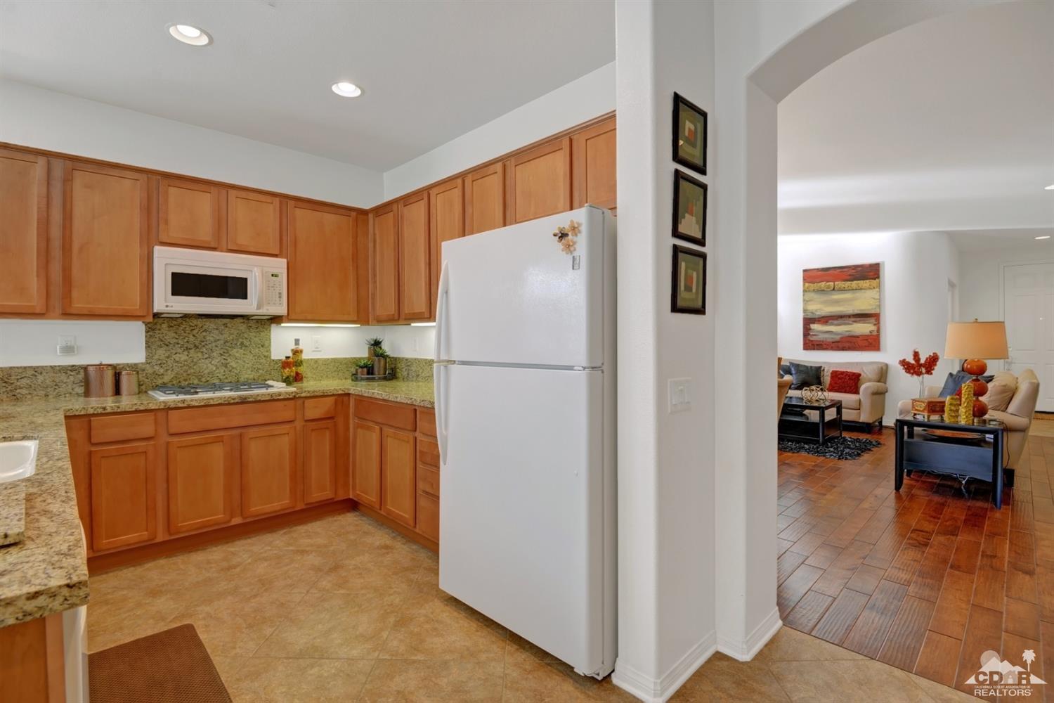 49568 Minelli Street Indio, CA 92201 - Photo 16 of 29 a kitchen with granite countertop a refrigerator stove top oven and cabinets