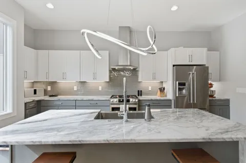a kitchen with stainless steel appliances granite countertop a sink a stove and a refrigerator