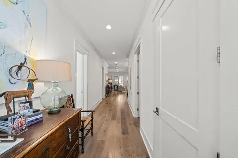 a view of a hallway to room with wooden floor and furniture