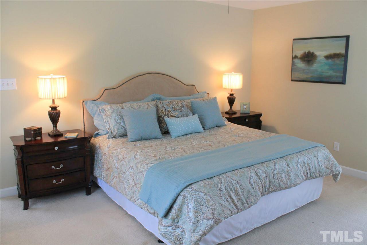 7712 Wilderness Road Raleigh, NC 27613 - Photo 14 of 25 a bedroom with a bed and a lamp