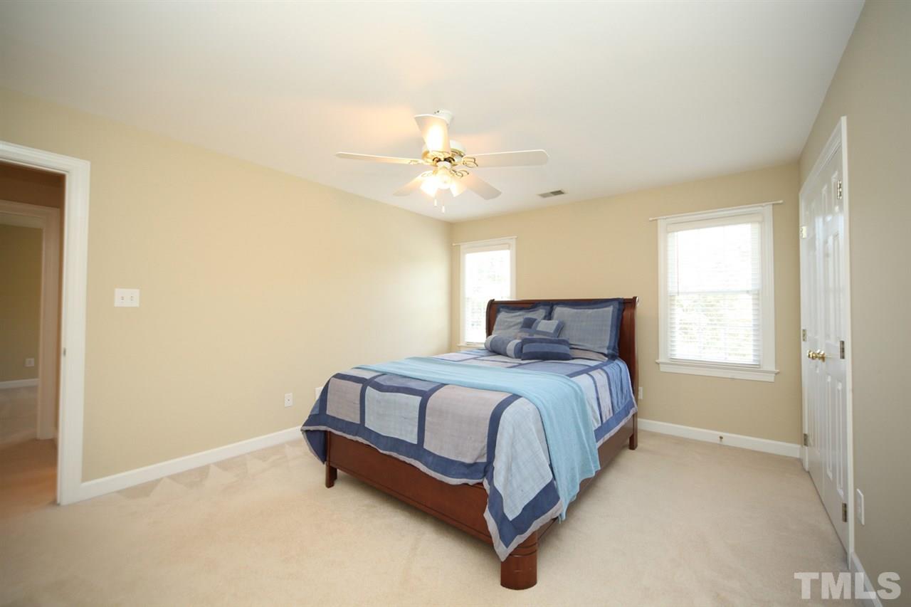 7712 Wilderness Road Raleigh, NC 27613 - Photo 17 of 25 a spacious bedroom with a bed and a ceiling fan