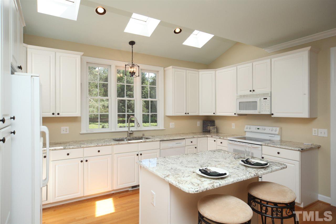7712 Wilderness Road Raleigh, NC 27613 - Photo 8 of 25 a kitchen with stainless steel appliances granite countertop a sink a stove a dining table and chairs