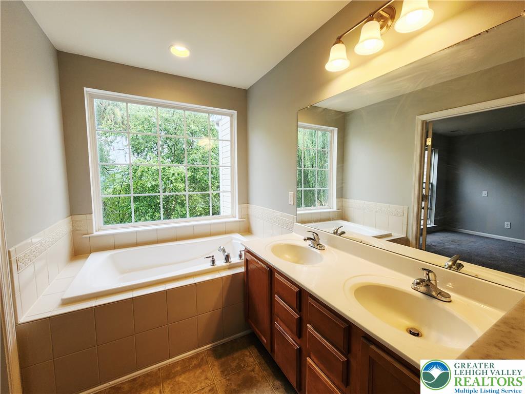 8513 Gateway Road Breinigsville, PA 18031 - Photo 32 of 45 Indulge in a tranquil bathing experience with a large soaking tub and dual vanity sinks set against a serene, tree-framed window.
