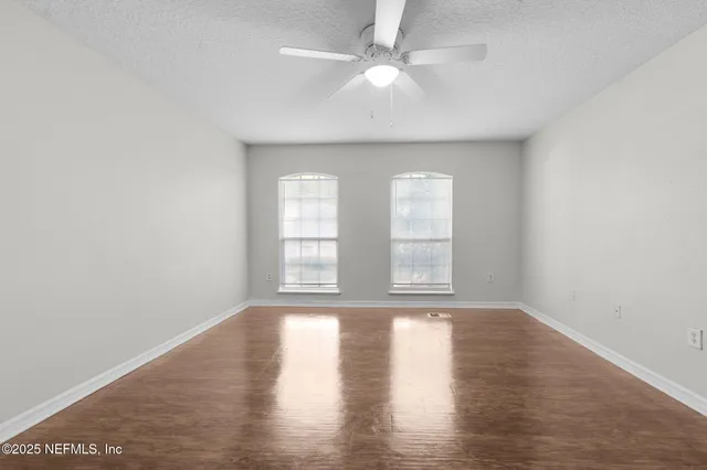 an empty room with wooden floor and windows
