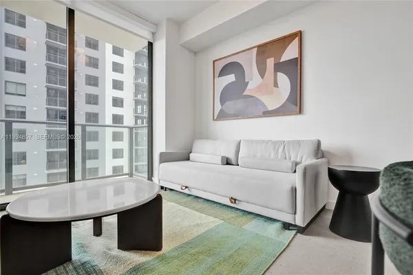 a dining room with furniture and a floor to ceiling window