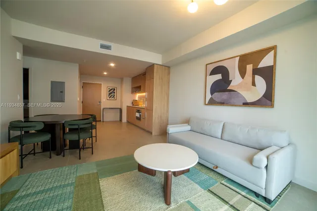 a living room with furniture and a dining table with bookshelf