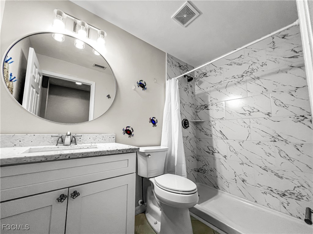 16285 Coco Hammock Way, Unit 101 Fort Myers, FL 33908 - Photo 16 of 50 a bathroom with a toilet a sink a mirror a shower and vanity