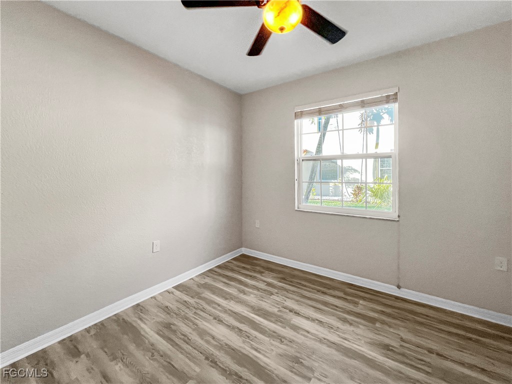 16285 Coco Hammock Way, Unit 101 Fort Myers, FL 33908 - Photo 22 of 50 an empty room with wooden floor and windows