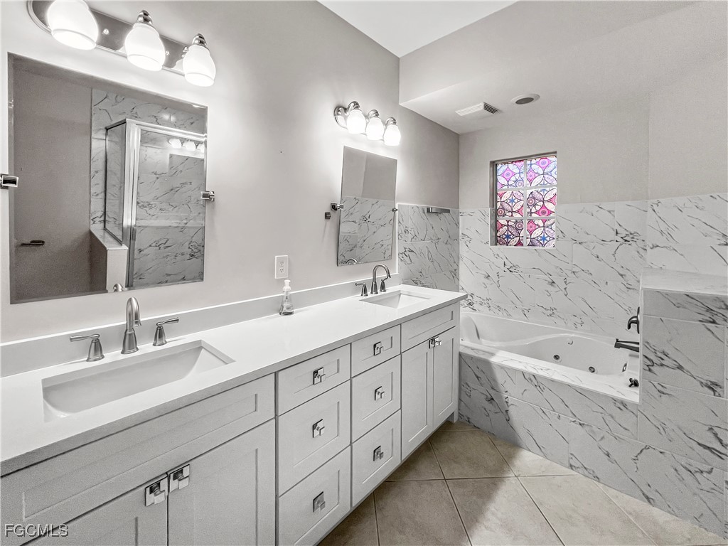 16285 Coco Hammock Way, Unit 101 Fort Myers, FL 33908 - Photo 27 of 50 a spacious bathroom with double sink a mirror a bathtub and next to a window