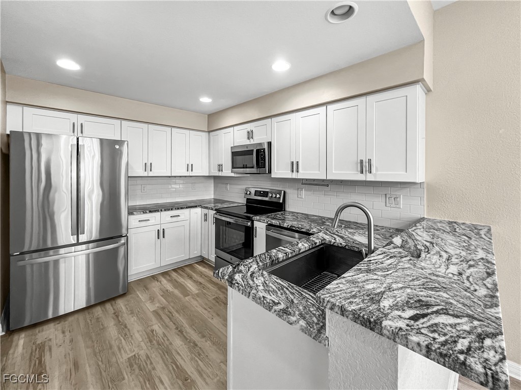 16285 Coco Hammock Way, Unit 101 Fort Myers, FL 33908 - Photo 10 of 50 a kitchen with stainless steel appliances granite countertop a refrigerator sink and cabinets
