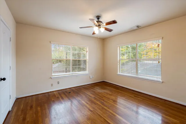 a view of an empty room with wooden floor and a window