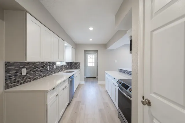 a kitchen with granite countertop a sink stove and cabinets