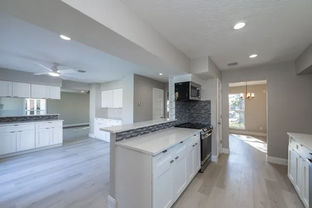 a large kitchen with stainless steel appliances granite countertop a lot of counter space and wooden floors