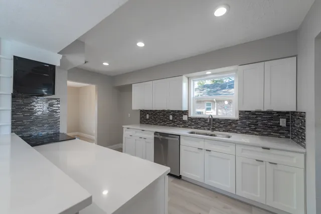 a kitchen with white cabinets and sink