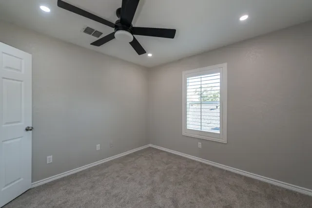 an empty room with a window and a fan