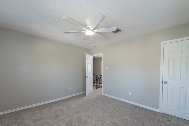 an empty room with closet and a ceiling fan