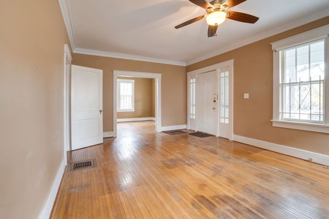 an empty room with wooden floor and windows