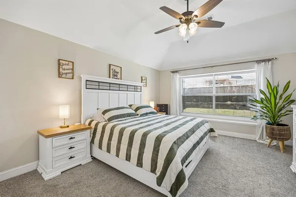 a bedroom with a large bed and a chandelier fan