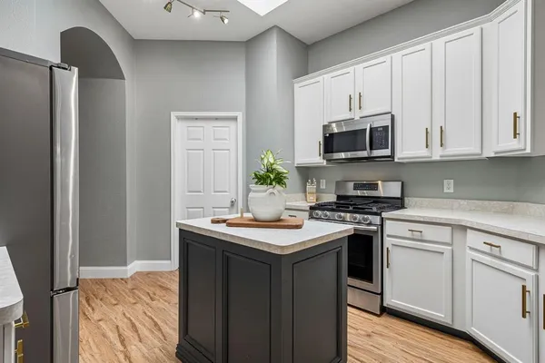 a kitchen with stainless steel appliances granite countertop a stove top oven a sink and dishwasher a refrigerator with wooden floor