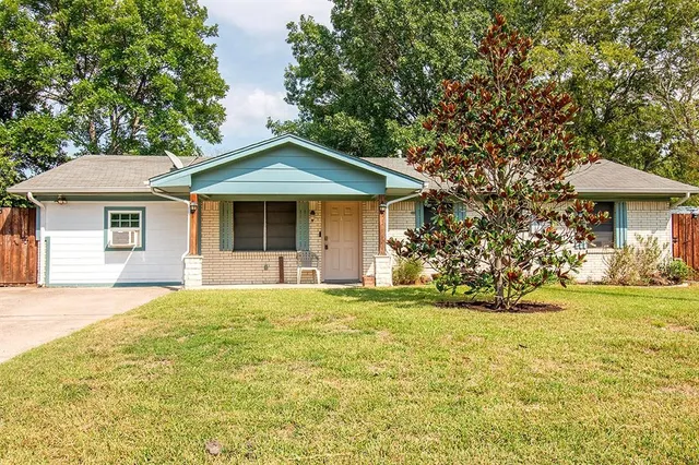 a front view of a house with a garden and trees