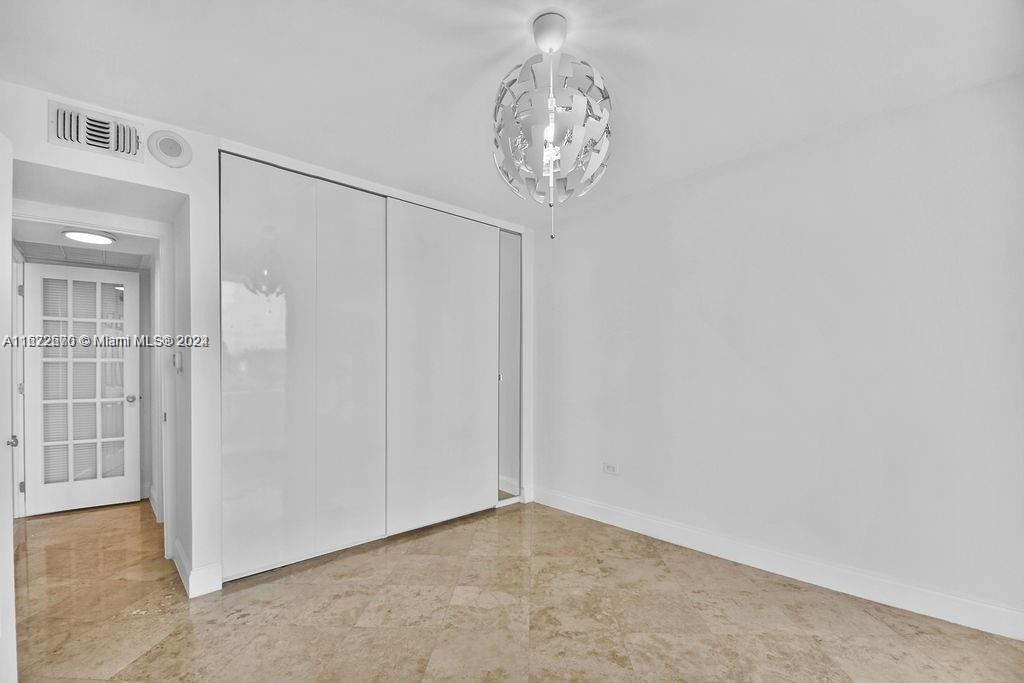 5555 Collins Avenue, Unit 5V Miami Beach, FL 33140 - Photo 24 of 46 an empty room with a chandelier fan and kitchen view