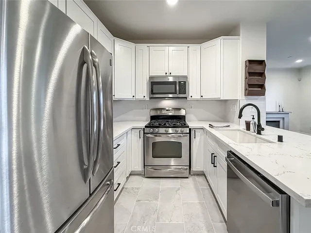 a kitchen with stainless steel appliances a refrigerator sink and white cabinets