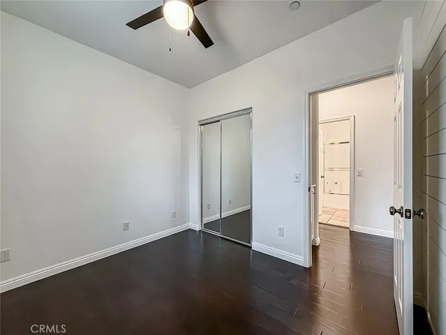an empty room with wooden floor and ceiling fan