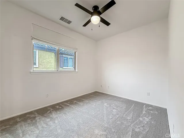 an empty room with a window and a ceiling fan