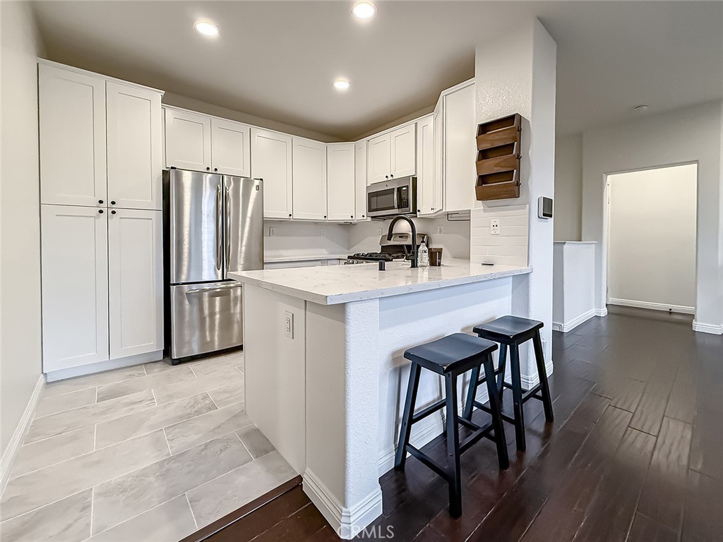 6834 Simmons Way Moorpark, CA 93021 - Photo 10 of 40 a kitchen with stainless steel appliances granite countertop a refrigerator a stove a sink dishwasher and microwave with wooden floor