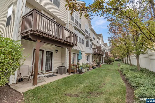 a view of a house with brick walls plants and large tree