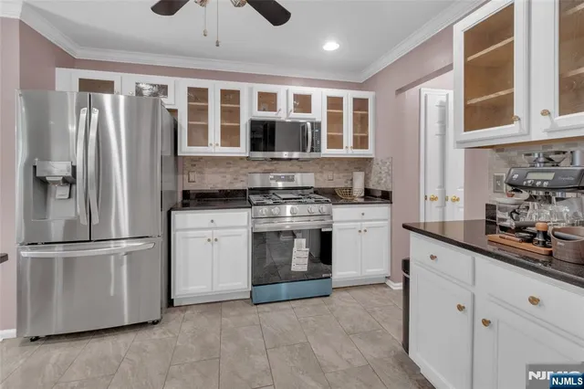 a kitchen with stainless steel appliances granite countertop a refrigerator a stove and a sink