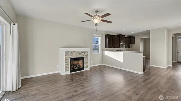 a view of a livingroom with a fireplace a ceiling fan and wooden floor