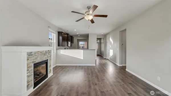 a view of a kitchen and an empty room with wooden floor a fireplace