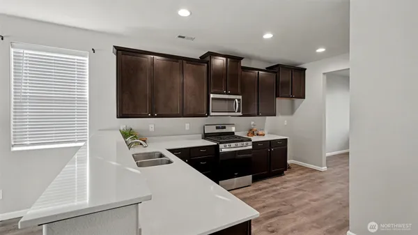 a kitchen with stainless steel appliances a sink a stove a microwave a refrigerator and cabinets