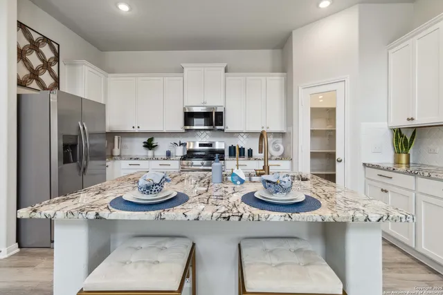 a kitchen with stainless steel appliances kitchen island granite countertop a sink stove refrigerator and cabinets