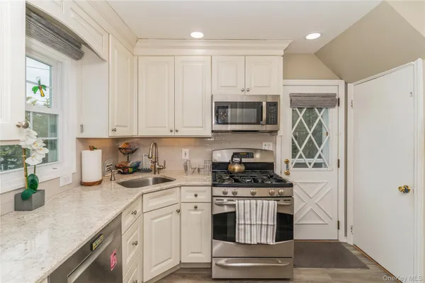 a kitchen with kitchen island granite countertop a stove top oven a sink a counter space and cabinets