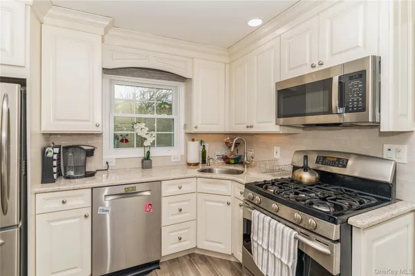 a kitchen with granite countertop white cabinets a window a sink and a stove