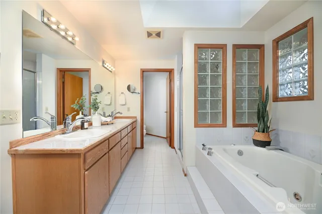 a bathroom with a bathtub a double vanity sink and a large mirror