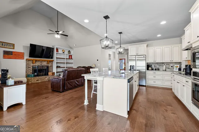 a living room with furniture kitchen view and a wooden floor