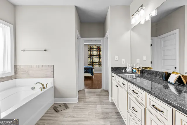 a spacious bathroom with a granite countertop sink mirror and a bathtub