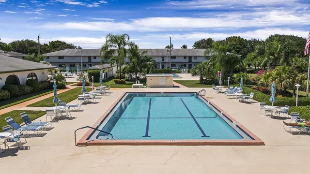 a view of a swimming pool with lawn chairs under an umbrella