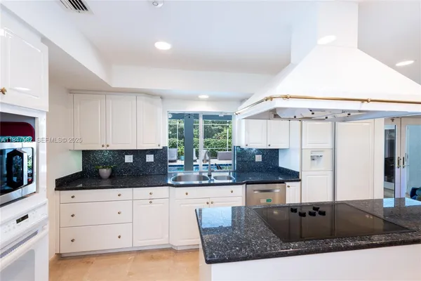 a kitchen with granite countertop a sink a stove and cabinets