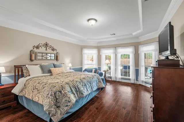 a bedroom with a large bed and a flat tv screen on dresser